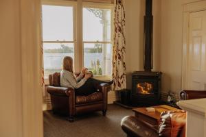 a woman sitting in a chair in a room with a fireplace at Beachfront Villa, Spacious, Mountain Outlook - KK87184 in Kaikoura