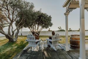 two people sitting on white chairs on a porch at Beachfront Villa, Spacious, Mountain Outlook - KK87184 in Kaikoura