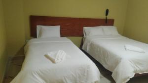 two beds in a hotel room with white sheets at Los ROYALS Hotel Huaraz in San Antonio