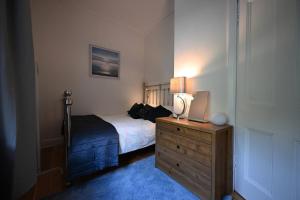 a bedroom with a bed and a dresser with a lamp at Harbour View - Waterfront Retreat, Rothesay in Rothesay