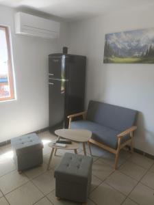 a living room with a couch and a table and a refrigerator at Gîte Le Domaine de Valko in Castanet-le-Haut