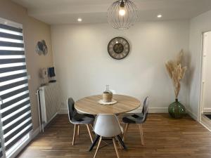 a dining room table with chairs and a clock on the wall at Maison Mara in Montliot-et-Courcelles