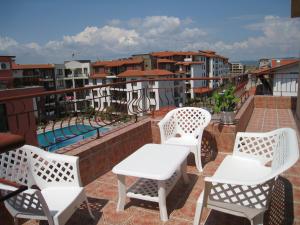 four white chairs and a table on a balcony at Complex Apolon in Nesebar