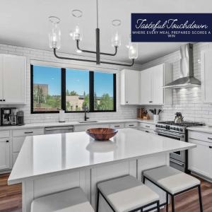 una cocina blanca con una gran isla blanca con taburetes en Luxury Alpine Abode, en Winter Park