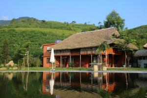 a house with an umbrella and a pond in front of it at SIM Farmstay in Ha Giang