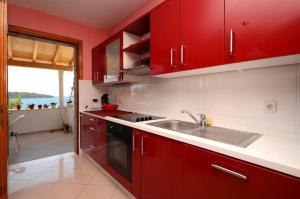 une cuisine avec des armoires rouges et un évier dans l'établissement Seaside holiday house Prizba, Korcula - 24637, à Blato