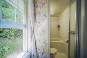 a bathroom with a shower curtain with a toilet and a window at 伊豆集 Episode IZU in Ito +160 photos