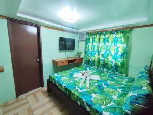 Un dormitorio pequeño con una cama con estampado tropical. en Blue Lagoon Inn and Restaurant, Pagudpud, en Mabubua