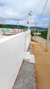eine weiße Wand mit Graffiti darauf neben einer Straße in der Unterkunft Vila Negreiros Serra Negra Casa 1 in Bezerros