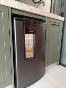 un frigorifero in acciaio inossidabile in una cucina con armadi verdi di Apartamento 2 suítes, Charme mediterrâneo, com Piscina e Academia a Itapema