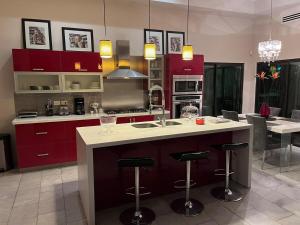 a kitchen with red cabinets and a island with bar stools at Modern and elegant house in Navojoa