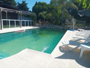 a swimming pool with two lawn chairs and a table and chairs at Cabañas La FLorencia in Magdalena