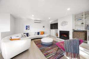 a living room with a white couch and a fireplace at Lookout and Sea - Beachfront Bliss in McCrae in McCrae