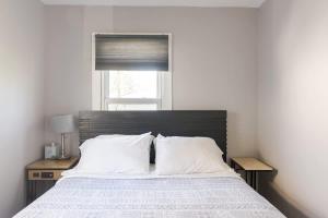 ein Schlafzimmer mit einem Bett mit weißen Laken und einem Fenster in der Unterkunft Corporate insurance or family vacation in Wolverine lake in Walled Lake