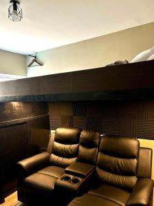 a leather couch in a living room with a ceiling at Cozy Studio near Nuvali, Enchanted Kingdom - Private Cinema with Netflix & Disney Plus with Free Pool Access in Silang