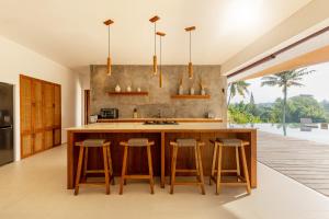 a kitchen with a large island with bar stools at IBU The Sanctuary by OXO in Ubud