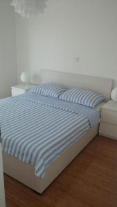 a bed with blue and white striped sheets and a couch at Malik's place in Novalja