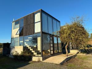 a house with glass windows and a tree at Cabañas Litueche 1 in El Rosario