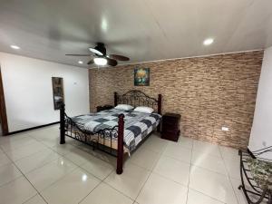a bedroom with a bed and a brick wall at Casa Bela in Parrita