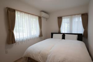 a bedroom with a white bed and two windows at 冬のソナタ1 in Nakafurano +17 photos