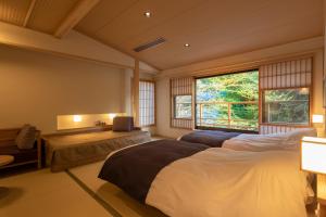 una camera da letto con due letti e due finestre di Yukairo Kikuya a Izu