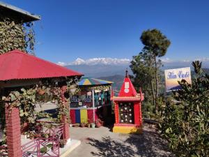 a group of colorful shops with mountains in the background at Himvadi Resort in Kausani