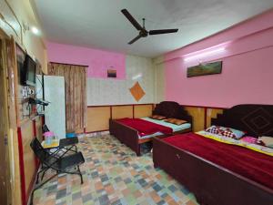 a bedroom with two beds and a ceiling fan at Himvadi Resort in Kausani
