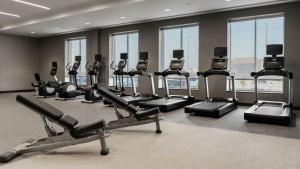 una palestra con tapis roulant ed ellittiche in una stanza con finestre di Courtyard by Marriott Madison Huntsville a Madison
