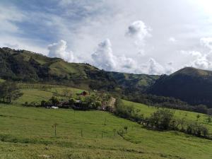 a green field with a farm in the distance at Las Bromelias in Coconuco