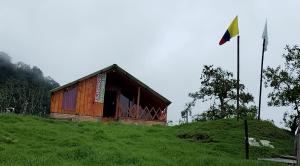 a small wooden building on a hill with a flag at Las Bromelias in Coconuco
