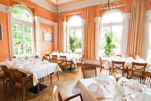 a restaurant with white tables and chairs and windows at Hotel Villa Dürkopp in Bad Salzuflen