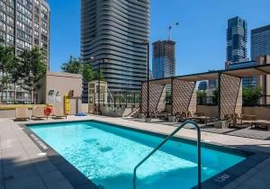 une piscine avec des chaises et un bâtiment dans l'établissement Stylish Stay with City Views, Pool and Gym, à Toronto