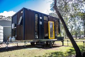 a black tiny house sitting on a table next to a tree at JJJ's Ranch Farm 1 by Tiny Away in Koolboo