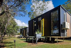 a black tiny house on a trailer with a table at JJJ's Ranch Farm 1 by Tiny Away in Koolboo