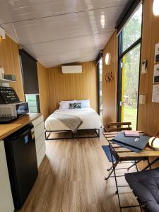 a bedroom with a bed and a desk and a kitchen at JJJ's Ranch Farm 1 by Tiny Away in Koolboo