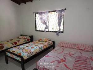 two beds in a room with a window and a window at Mágica Cabaña familiar cerca al mar in Coveñas