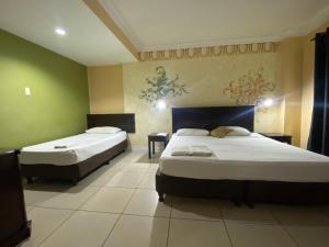 two beds in a room with green walls at Hotel Euroasia By BLUEBOOKERS in Angeles