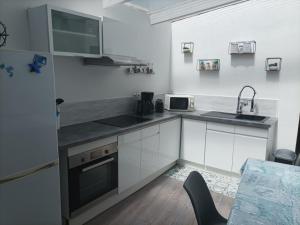 a kitchen with white cabinets and a sink and a microwave at Le Croisic : Maison 4-6 Pers Climatisée avec Terrasse - FR-1-843-7 in Le Croisic