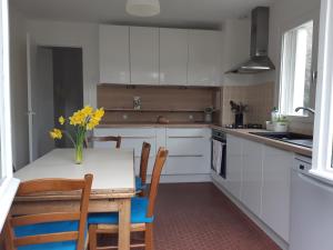eine Küche mit weißen Schränken und einem Tisch mit gelben Blumen in der Unterkunft Maison 6 pers près des marais salants à Batz-sur-Mer - FR-1-843-26 in Batz-sur-Mer