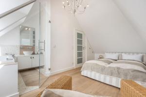a white bedroom with a bed and a sink at Lands-End in Hörnum