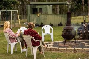 two people sitting in chairs next to a fire pit at JJJ's Ranch Farm 1 by Tiny Away in Koolboo