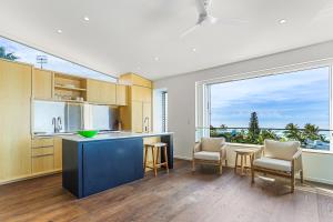 una cucina con isola blu e grande finestra di Ultimate Beachfront Living Sunshine Beach a Sunshine Beach