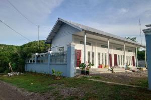 a white house with red doors and a yard at Phnom Sampov Homestay ផ្ទះលំហែភ្នំសំពៅ in Phumĭ Kdaông Khang Tbong