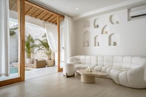 a living room with a white couch and a table at Villa Estrella Seseh in Cemagi +18 photos