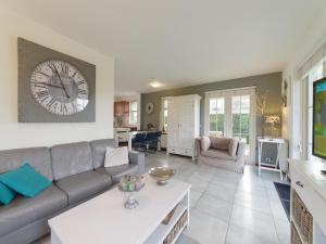 a living room with a couch and a clock on the wall at Charming Coastal Escape in Wemeldinge