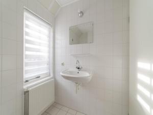 a white bathroom with a sink and a window at Charming Coastal Escape in Wemeldinge +32 photos