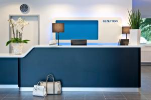 a blue reception desk with a computer on top at ibis budget Duisburg City am Innenhafen in Duisburg