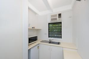 Una cocina blanca con fregadero y microondas. en Unit 136 Amaroo Standard Twin Studio Apartment, en Nelly Bay
