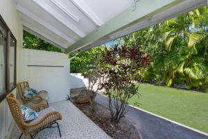 Un porche con dos sillas de mimbre en un patio. en Unit 136 Amaroo Standard Twin Studio Apartment, en Nelly Bay
