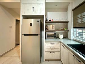 a white kitchen with a refrigerator and a microwave at Melodies Moderne 2B2B Near HolidayPlaza KSL in Johor Bahru